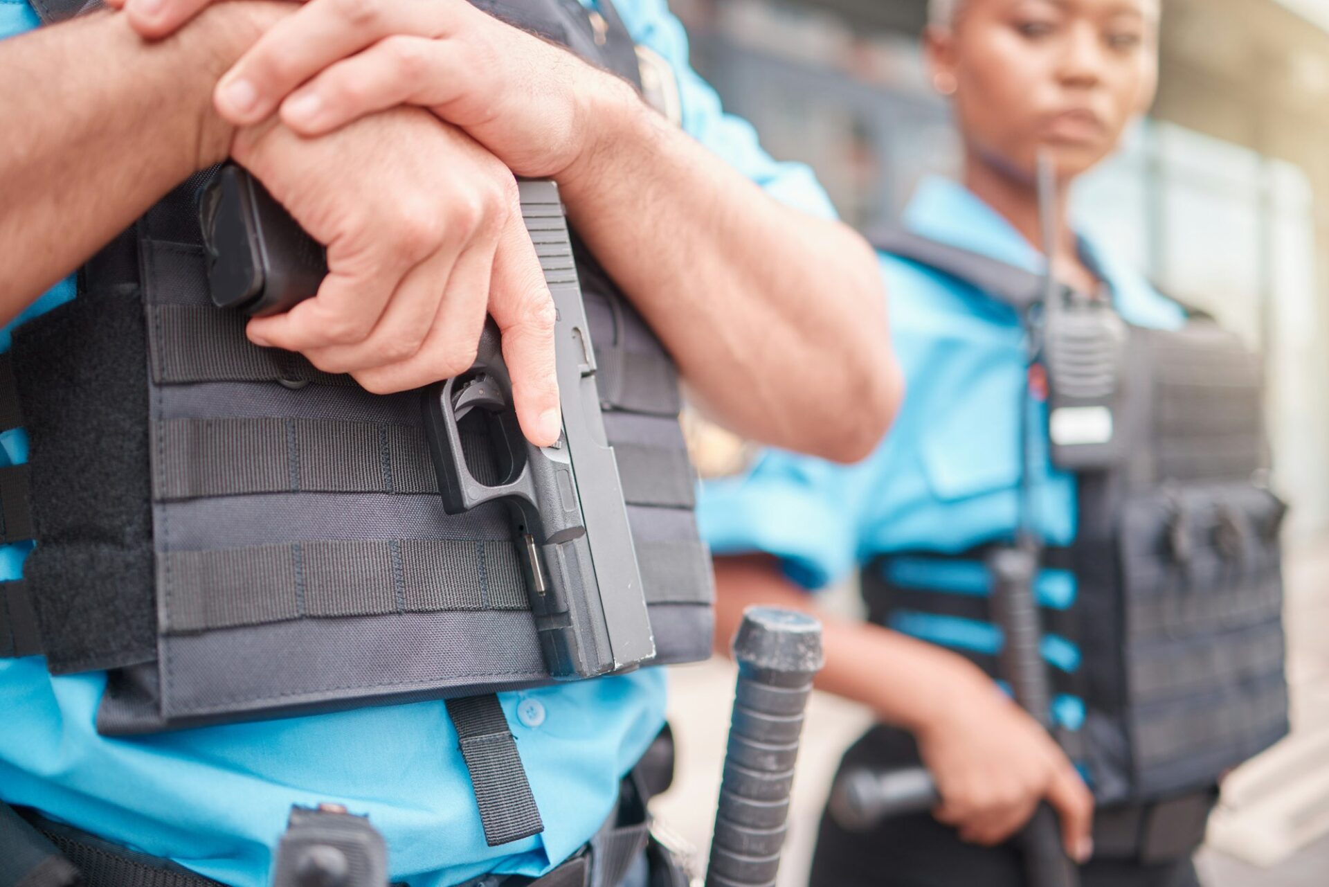 Police, hand and gun with a law enforcement officer standing outdoor in the city while on patrol cl